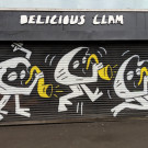 Shop shutters painted with three clam characters, each playing a saxophone in different poses